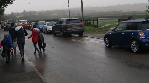 Pedestrians with children walking on a busy road in the parish 